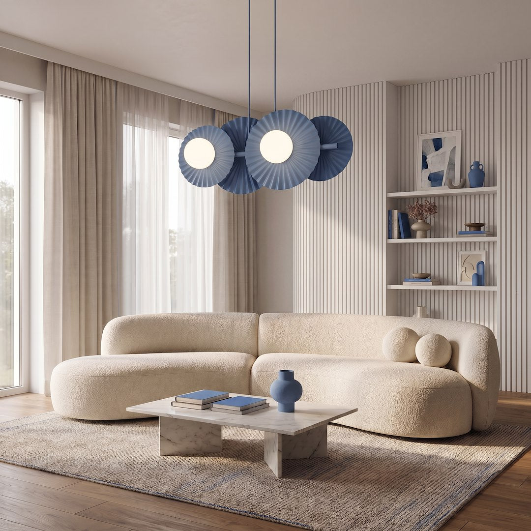 Luminaire suspendu bleu éclairant un salon avec canapé beige et table basse.