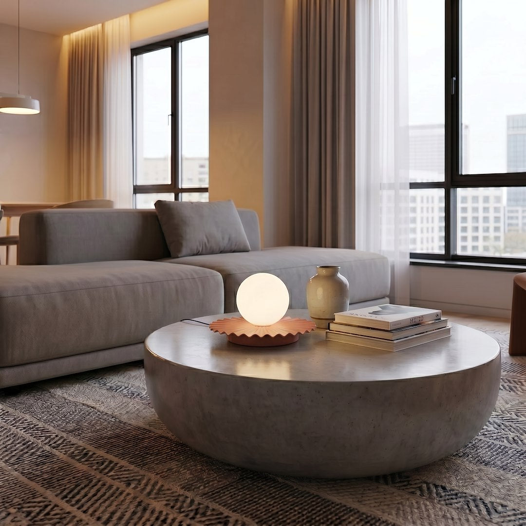 Mise en ambiance, lampe allumée sur table en béton devant un canapé beige
