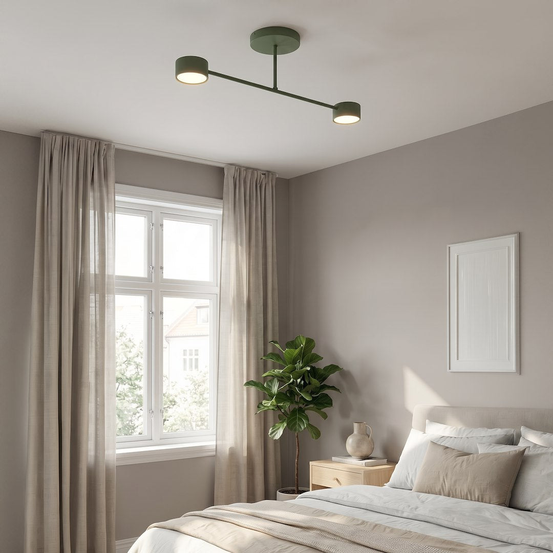 Mise en ambiance dans une chambre claire, plafonnier vert allumé au-dessus du lit.