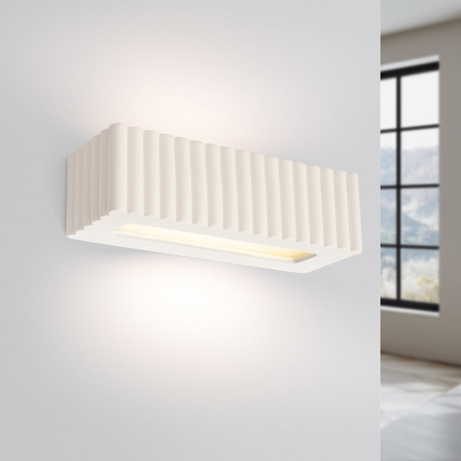Même applique murale allumée diffusant un halo de lumière chaude sur le mur.
