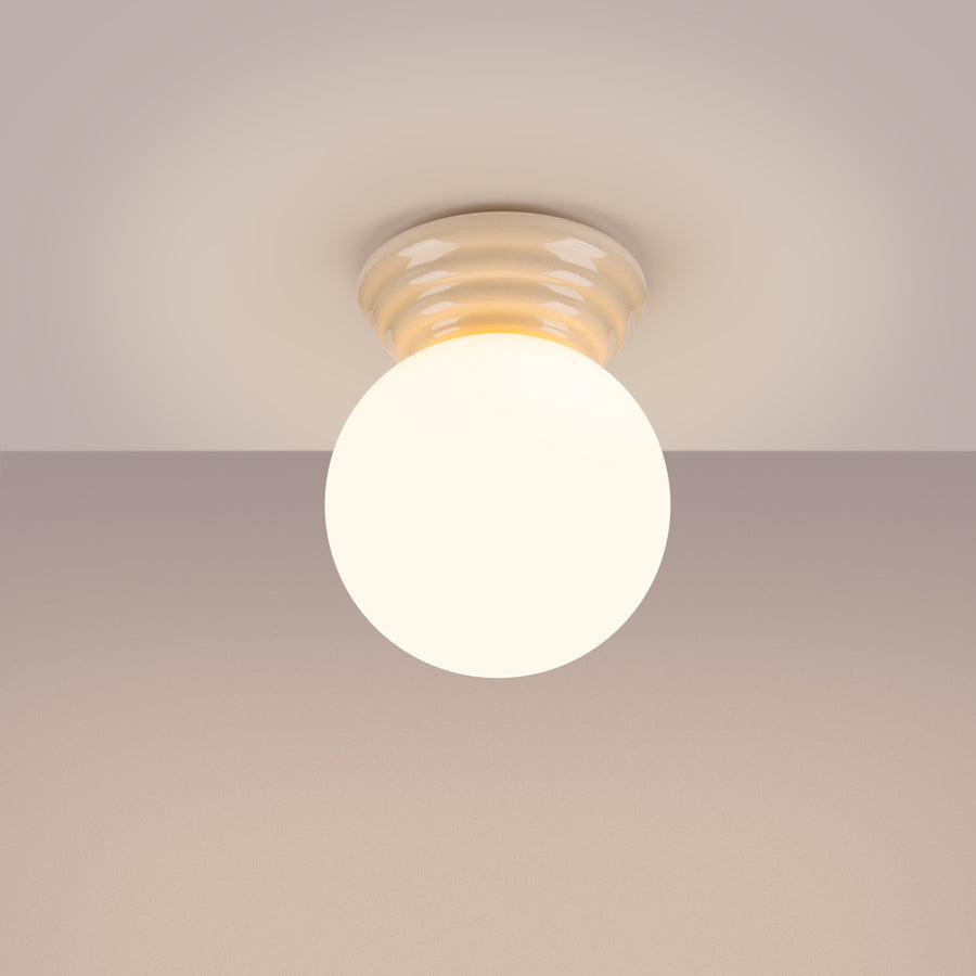 Plafonnier allumé au plafond, lumière chaude diffusée par le globe.