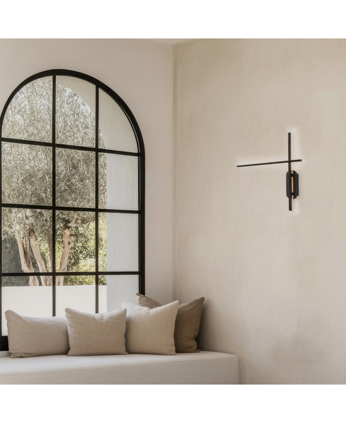 Ambiance minimaliste avec applique murale noire allumée et grande fenêtre arquée
