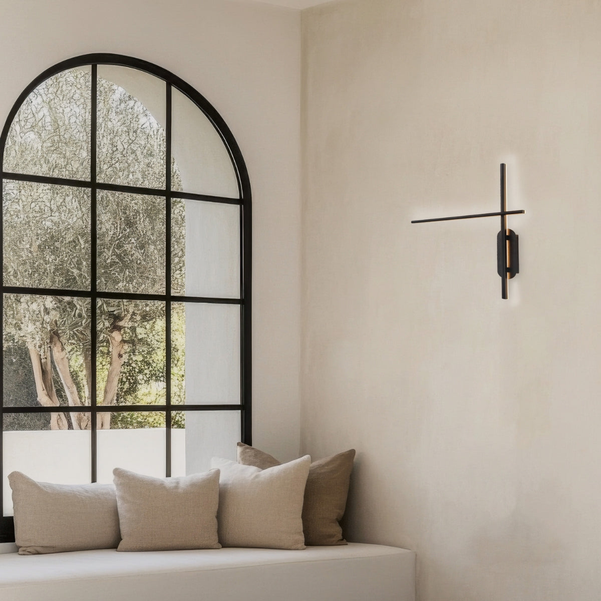 Vue rapprochée de l'applique noire sur un mur beige devant une fenêtre cintrée