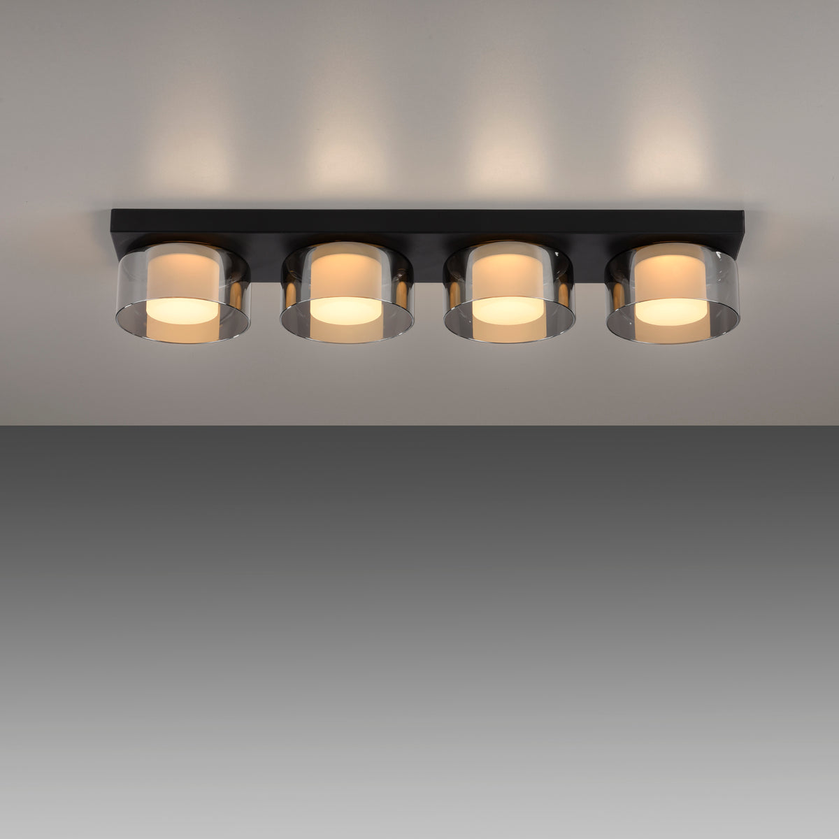 Plafonnier allumé au plafond sur fond gris, diffusant une lumière chaude en halo
