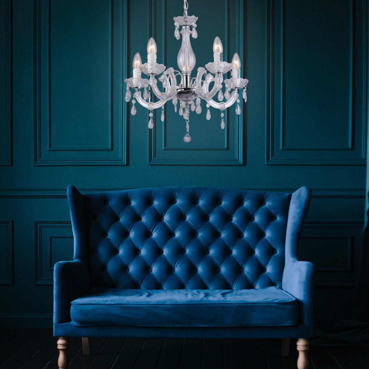 Mise en ambiance du luminaire suspendu devant un mur bleu et un canapé velours.