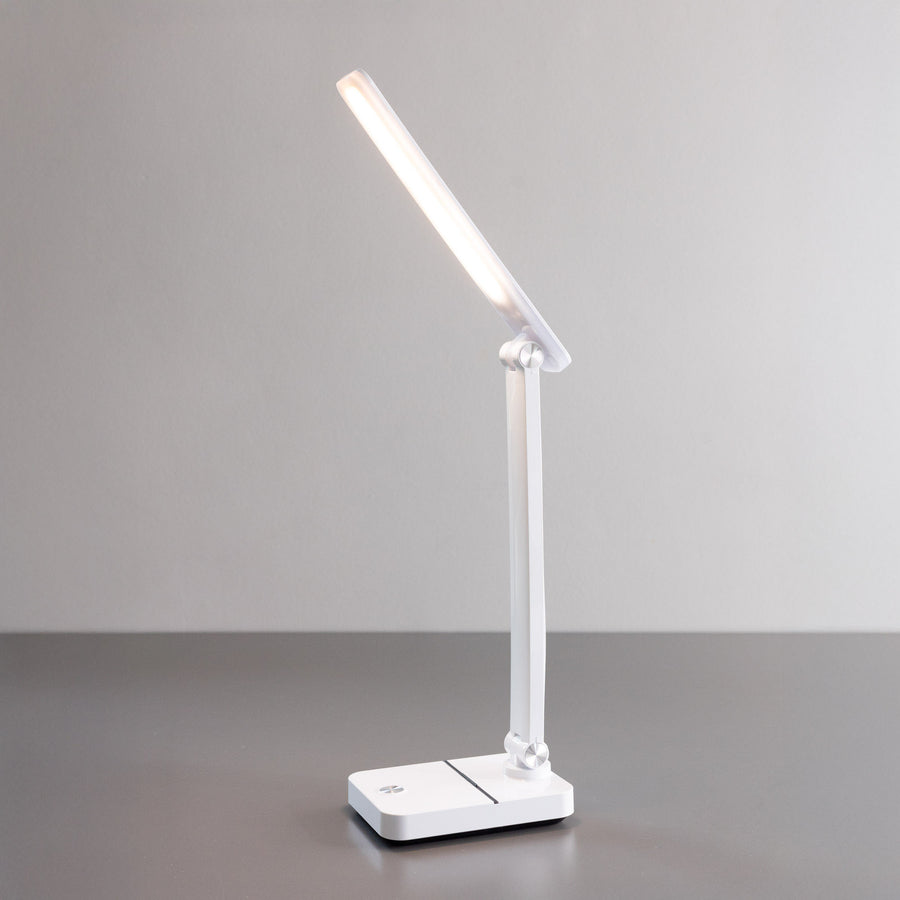 Lampe de bureau blanche allumée, vue de face sur fond gris clair