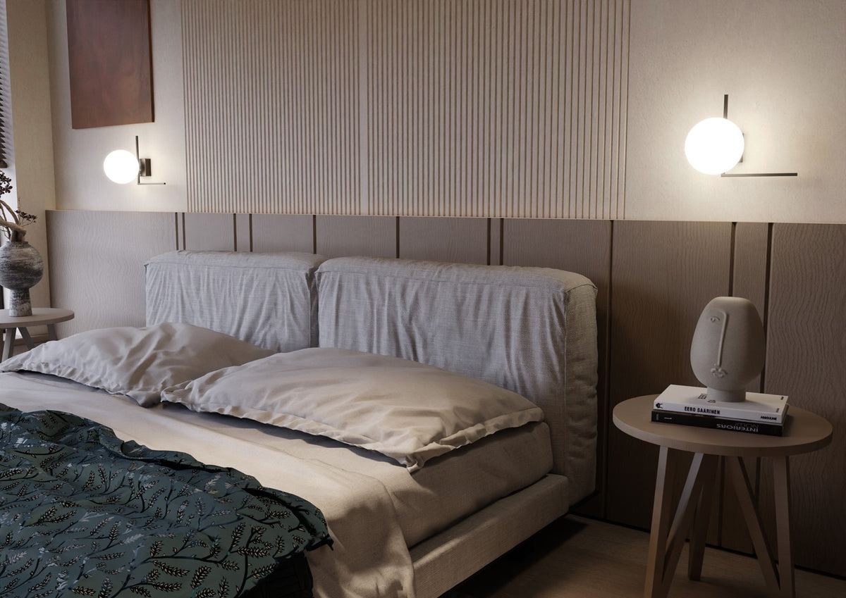 Deux appliques éclairées de part et d'autre d'un lit à tête de tissu gris