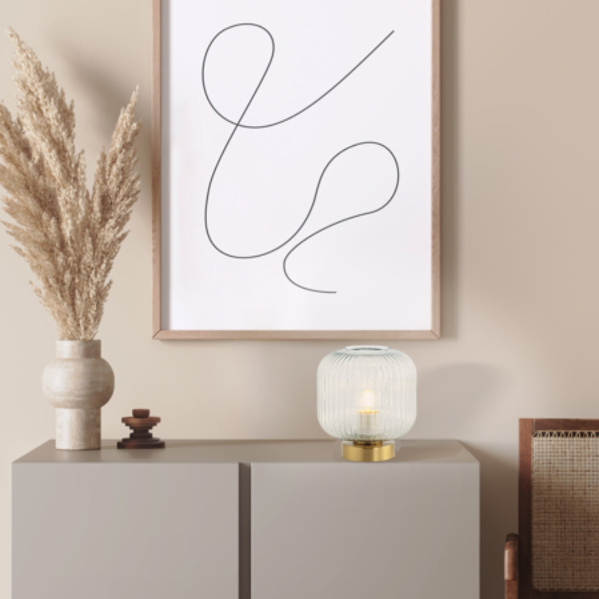 Scène déco avec vase en céramique, herbes séchées et lampe posée sur le buffet