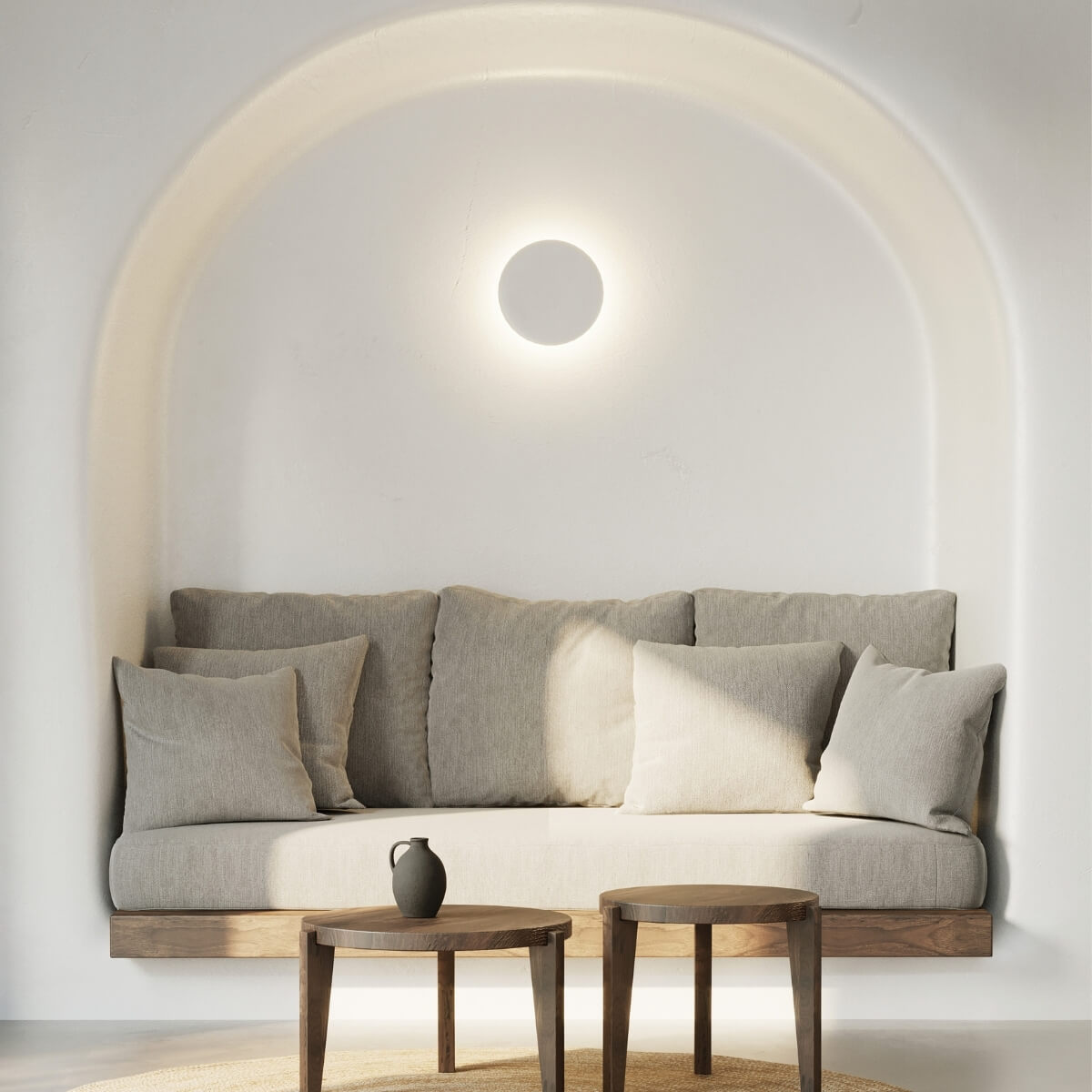 Vue large de la niche blanche avec applique ronde allumée, canapé et coussins