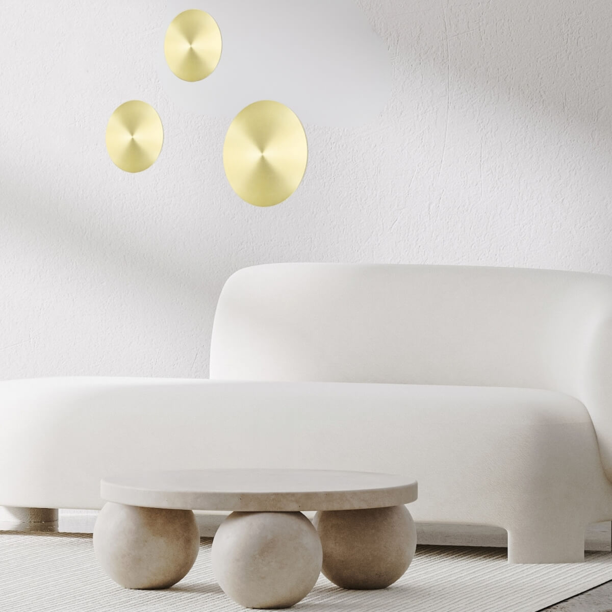 Mise en ambiance avec trois appliques rondes en laiton brossé sur mur blanc.