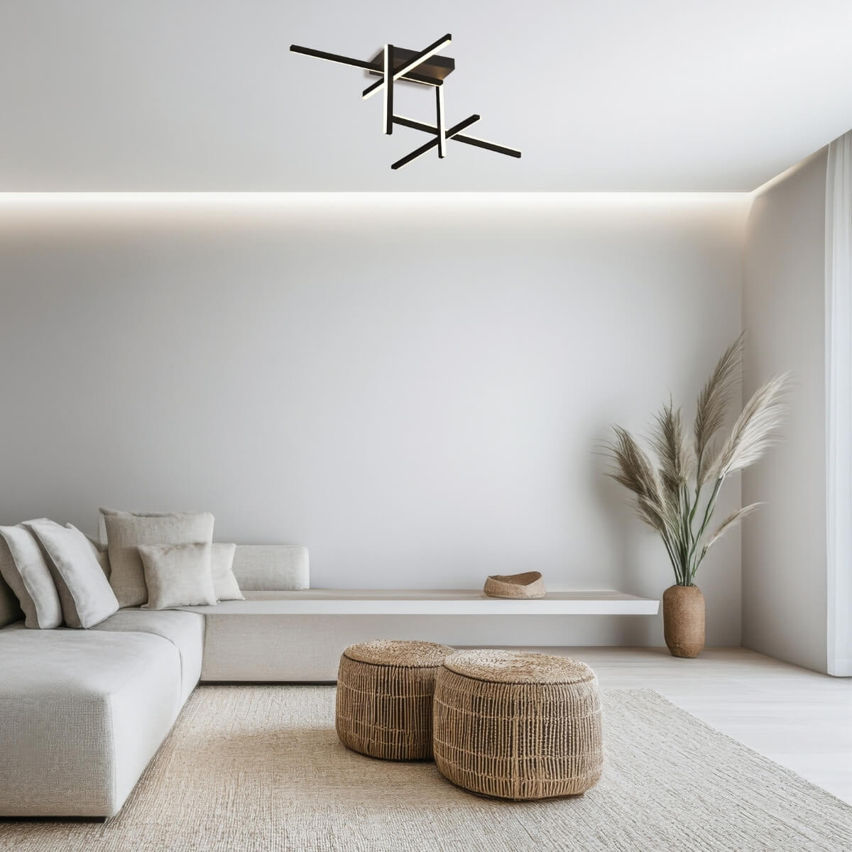 Vue d'ensemble d'un salon blanc avec plafonnier design noir, grands poufs et vase d'herbes.