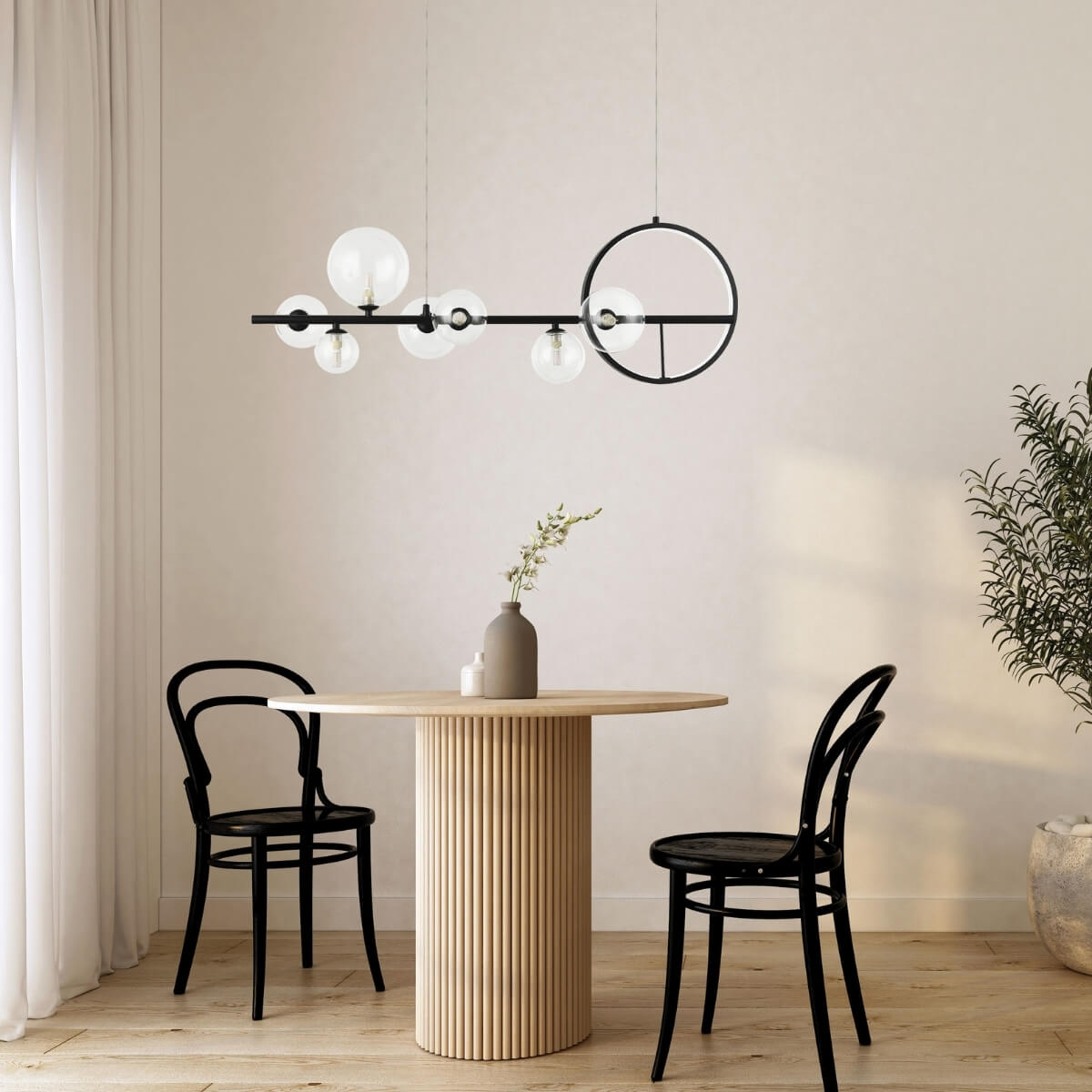 Vue en situation du luminaire au-dessus d'une table et deux chaises noires.