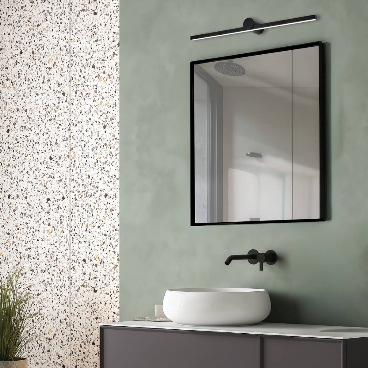 Gros plan sur l'applique allumée et le miroir à cadre noir