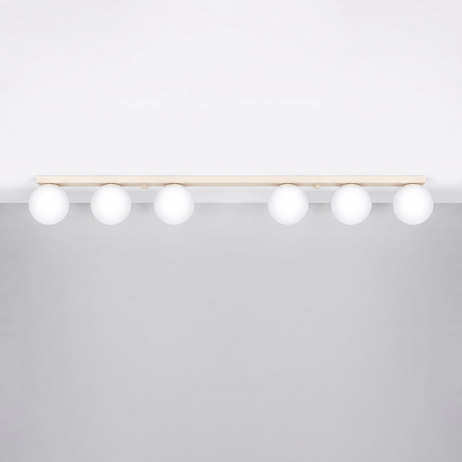 Luminaire installé au plafond, six globes blancs suspendus sous une barre beige.