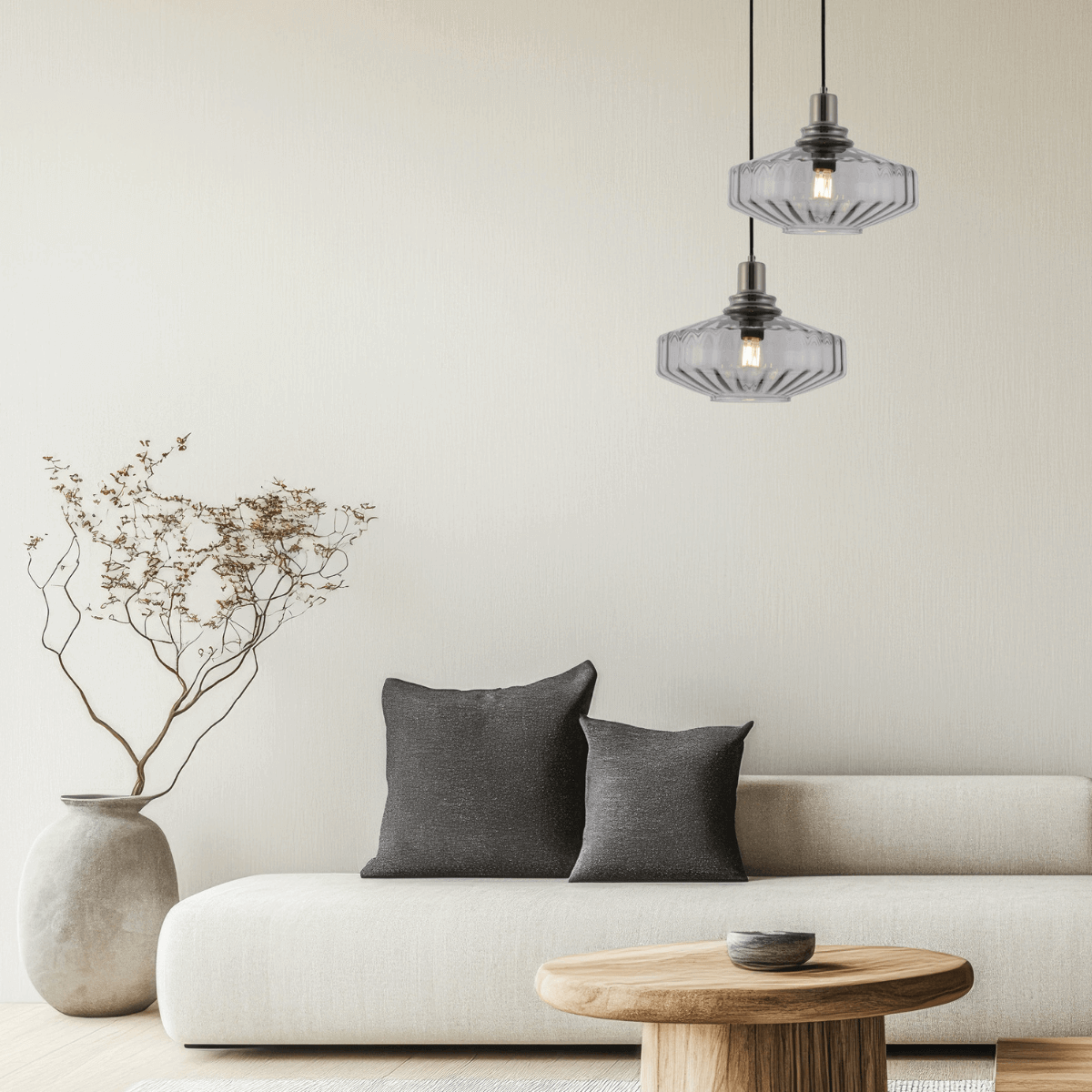 Intérieur épuré montrant deux luminaires suspendus éclairés, canapé, coussins gris et table