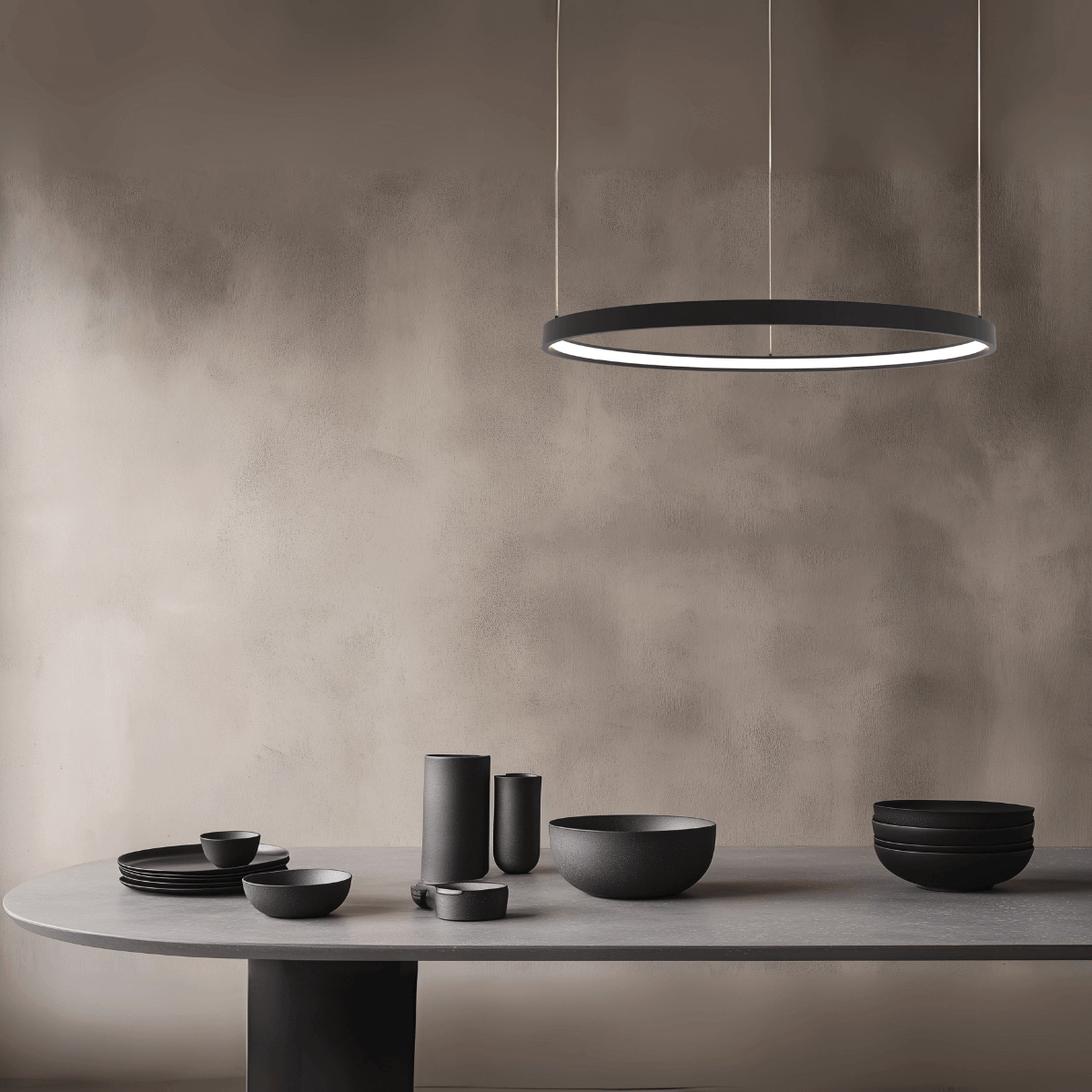 Vue rapprochée de la table en béton et de la suspension circulaire en noir mat