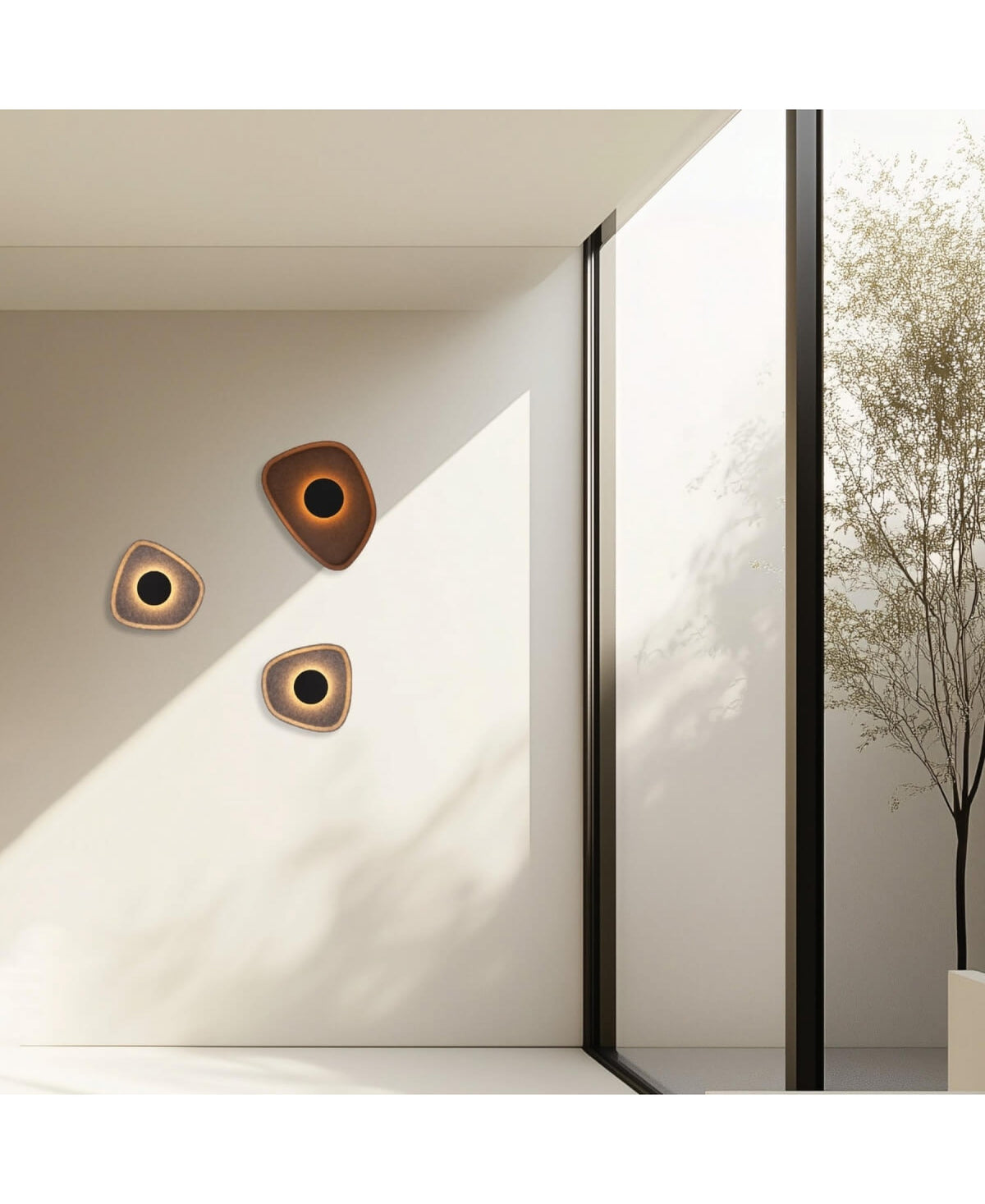 Vue d'ensemble d'un mur clair orné de trois appliques design, ombres du feuillage