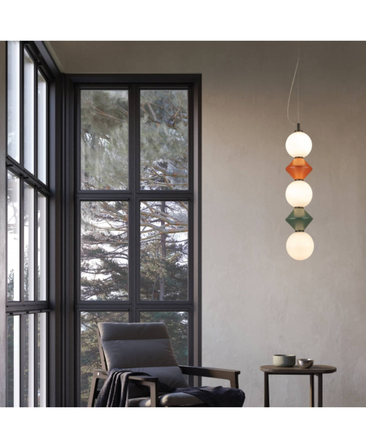 Mise en ambiance du luminaire suspendu près d'une grande fenêtre et d'un fauteuil.