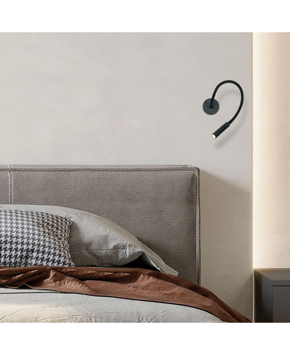 Vue de la lampe murale noire dans une chambre, près des coussins et d'une couverture.