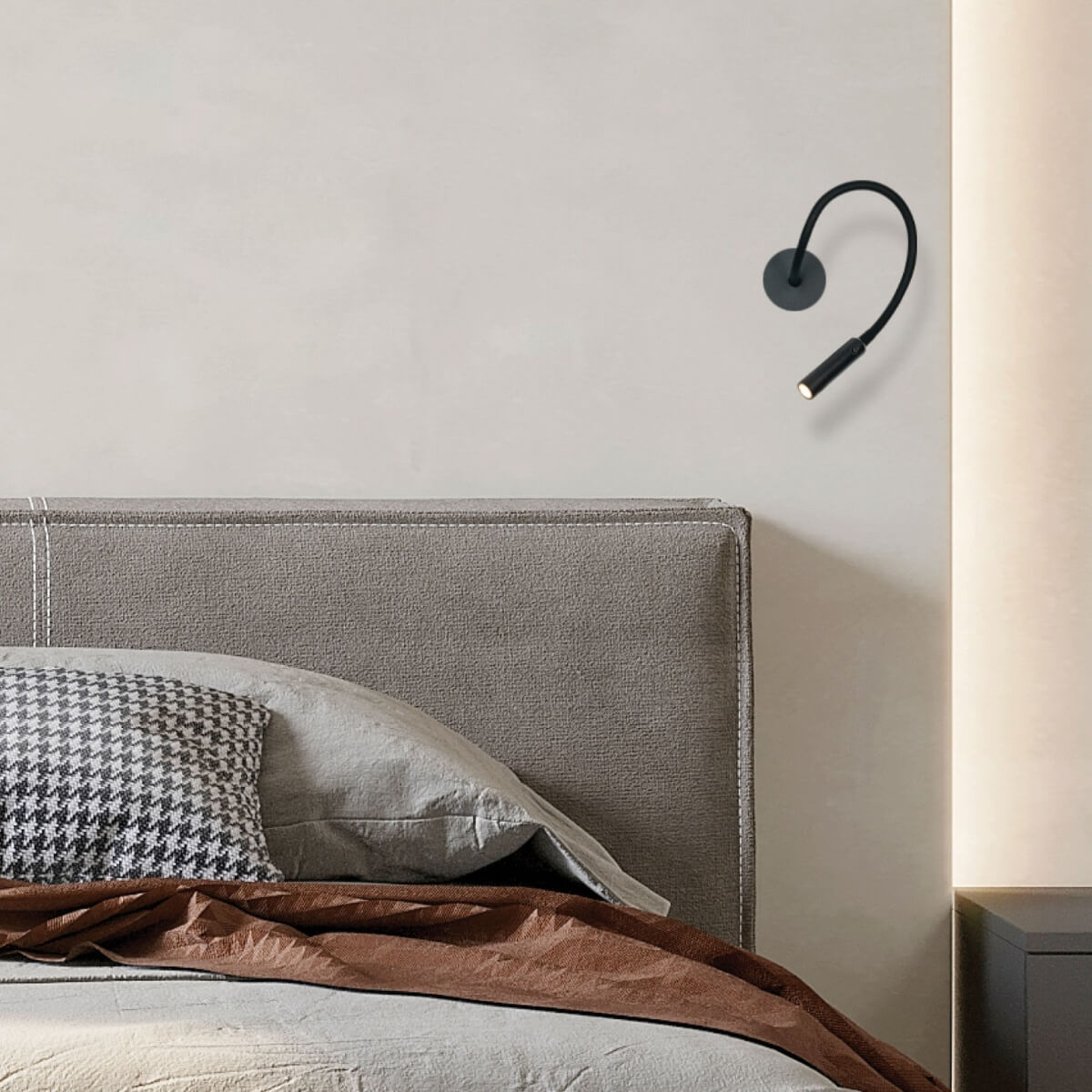 Plan rapproché sur l'applique murale et la tête de lit dans une chambre.
