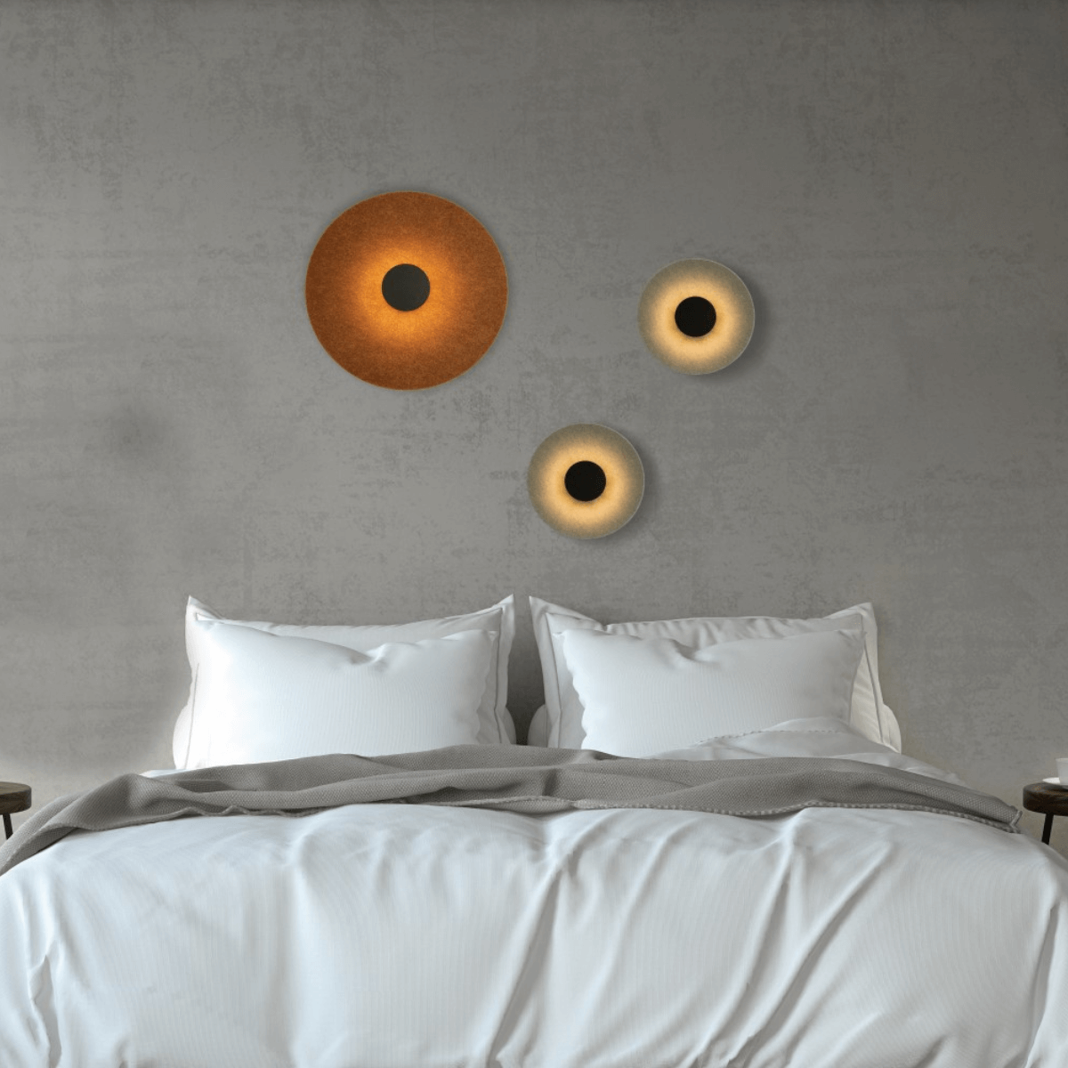 Ambiance chambre avec trois appliques acoustiques allumées sur mur béton gris