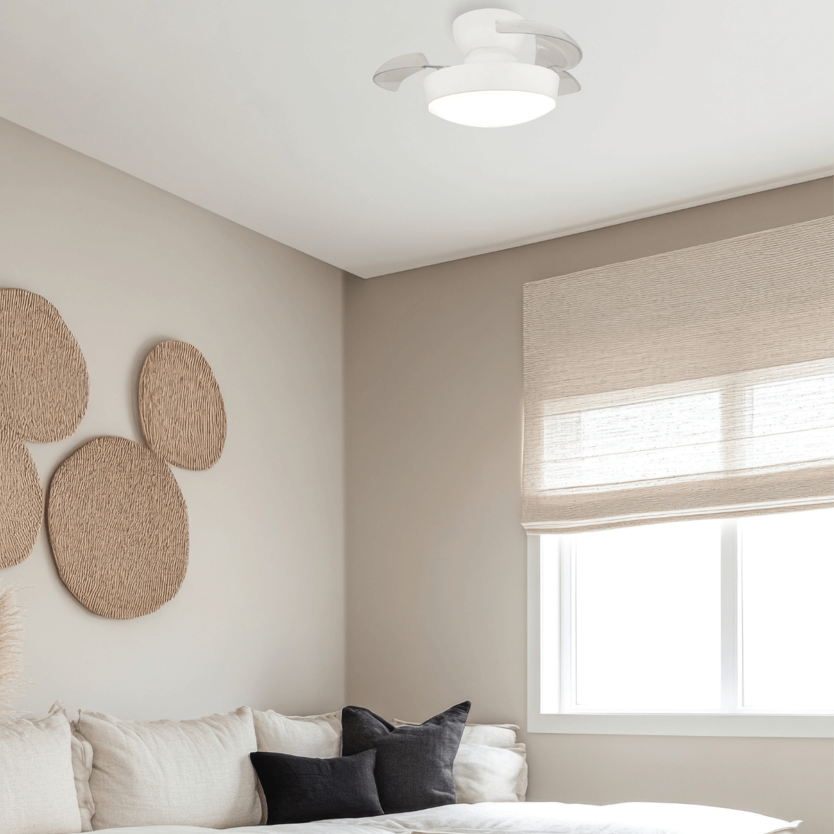 Vue du ventilateur de plafond blanc dans une chambre, au-dessus d'un lit avec coussins.