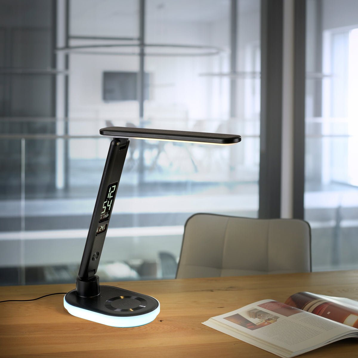 Mise en ambiance sur bureau en bois dans un open space, lampe allumée avec socle lumineux.