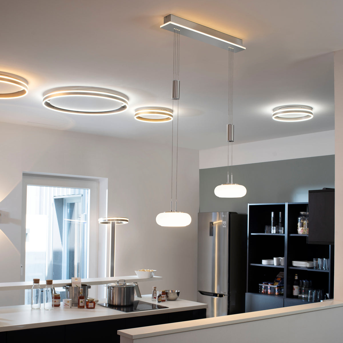 Mise en ambiance dans une cuisine moderne avec suspension allumée au-dessus de l'îlot