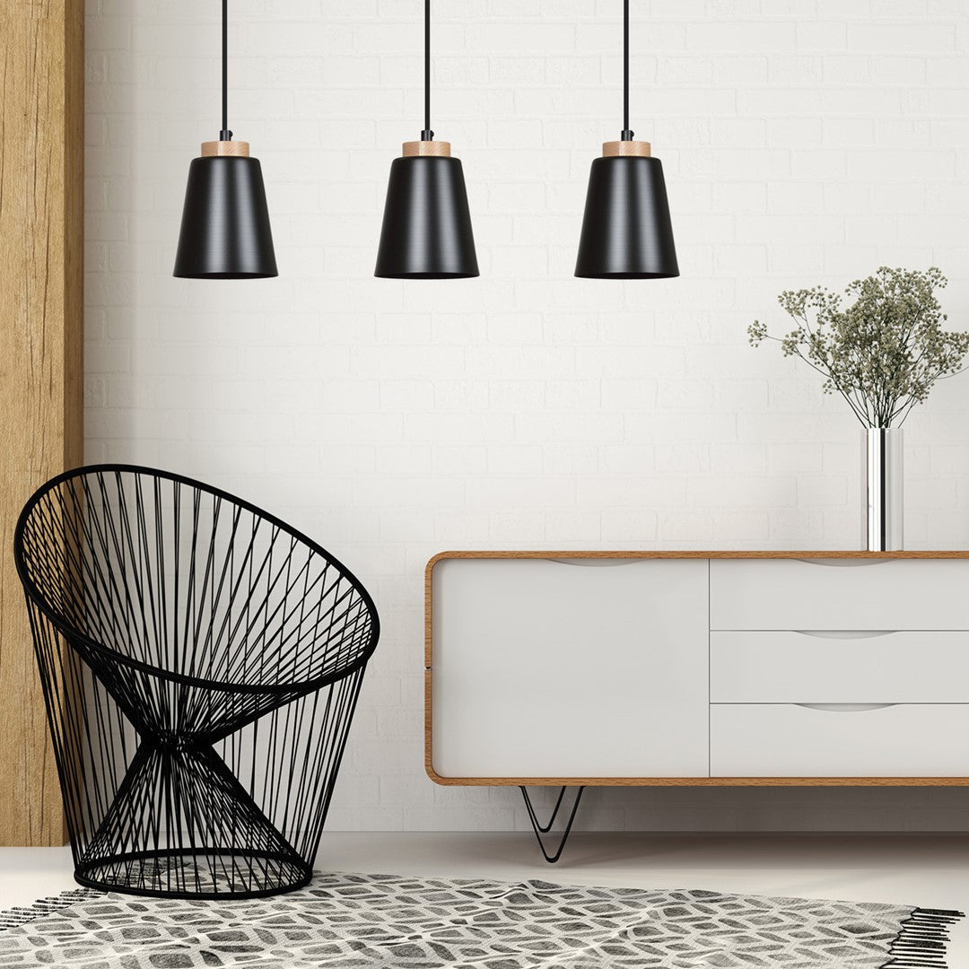 Mise en ambiance dans un salon avec fauteuil noir, meuble blanc et vase de fleurs séchées.