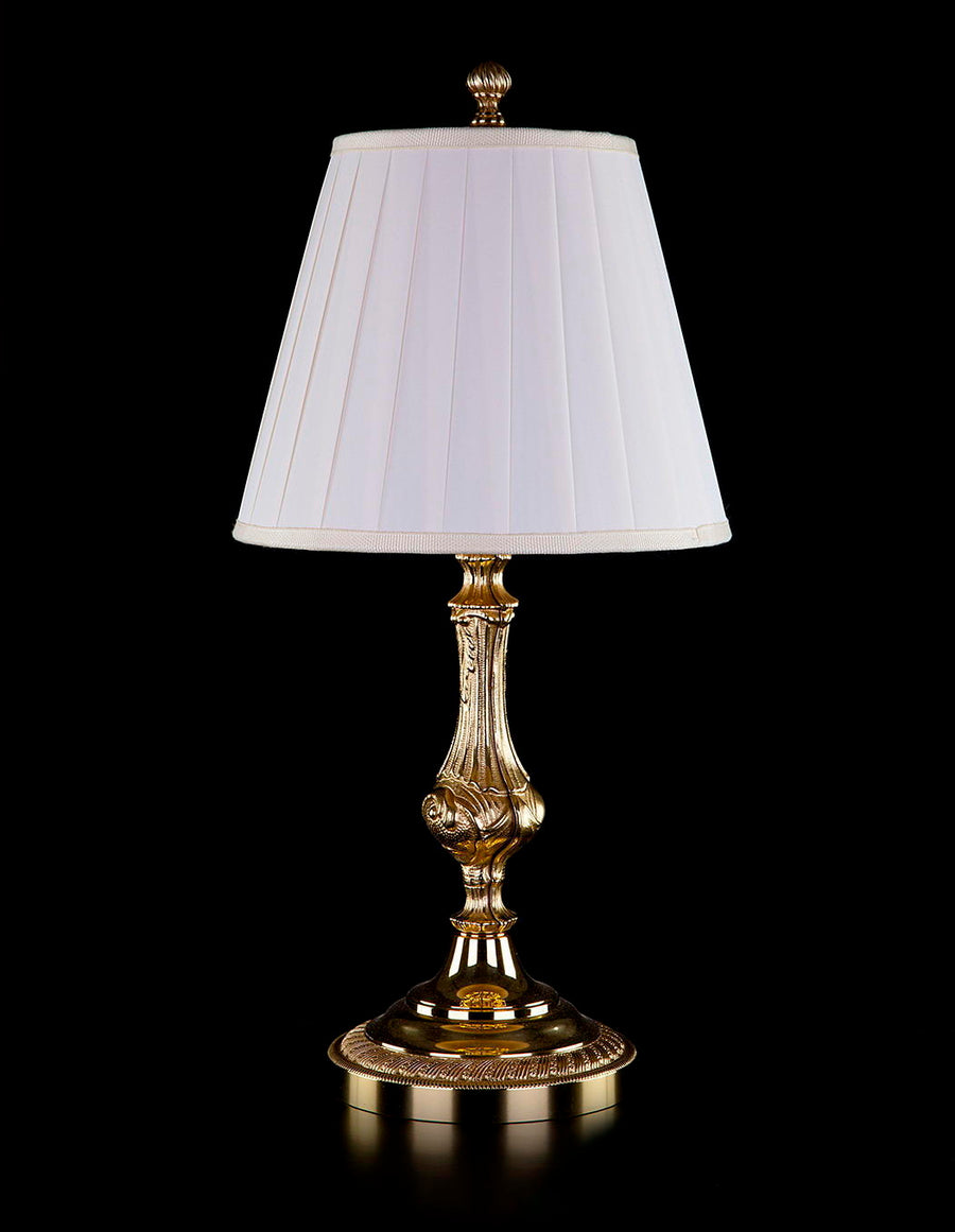 Lampe à poser dorée de face, abat-jour plissé blanc sur fond noir