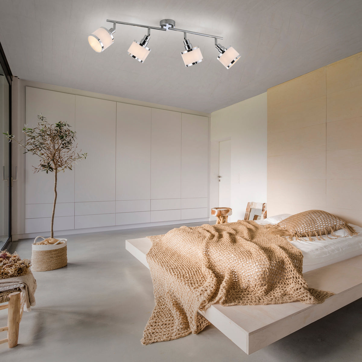 Plafonnier chromé installé au plafond d'une chambre claire, éclairant la pièce au-dessus du lit.