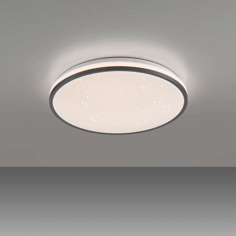 Plafonnier allumé fixé au plafond gris, halo lumineux diffus tout autour