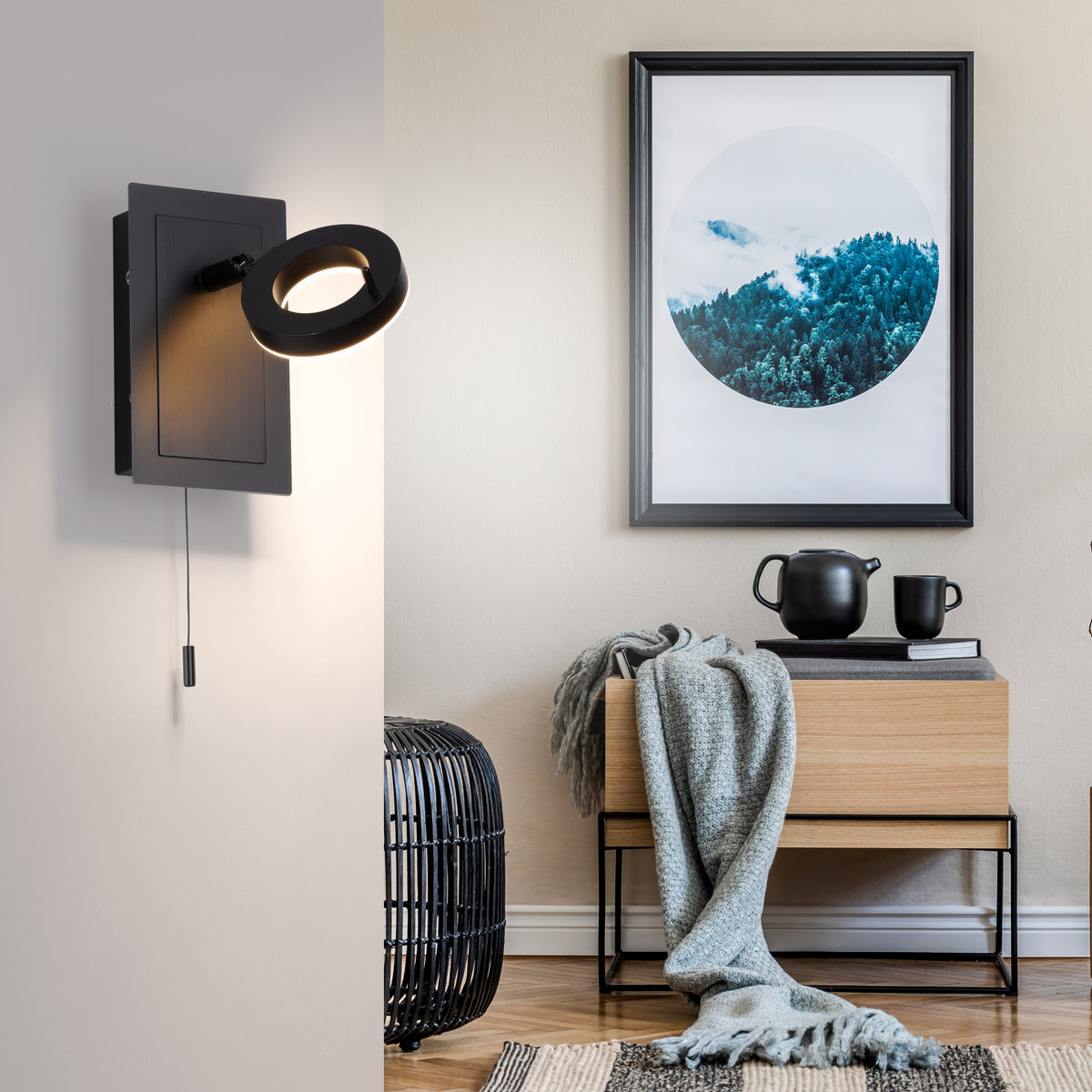 Mise en ambiance dans un salon, applique murale éclairant un mur près d'un cadre et d'un meuble