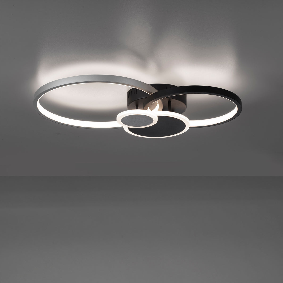 Luminaire en fonctionnement fixé au plafond, éclairage diffusant une lumière chaude et ombres portées.