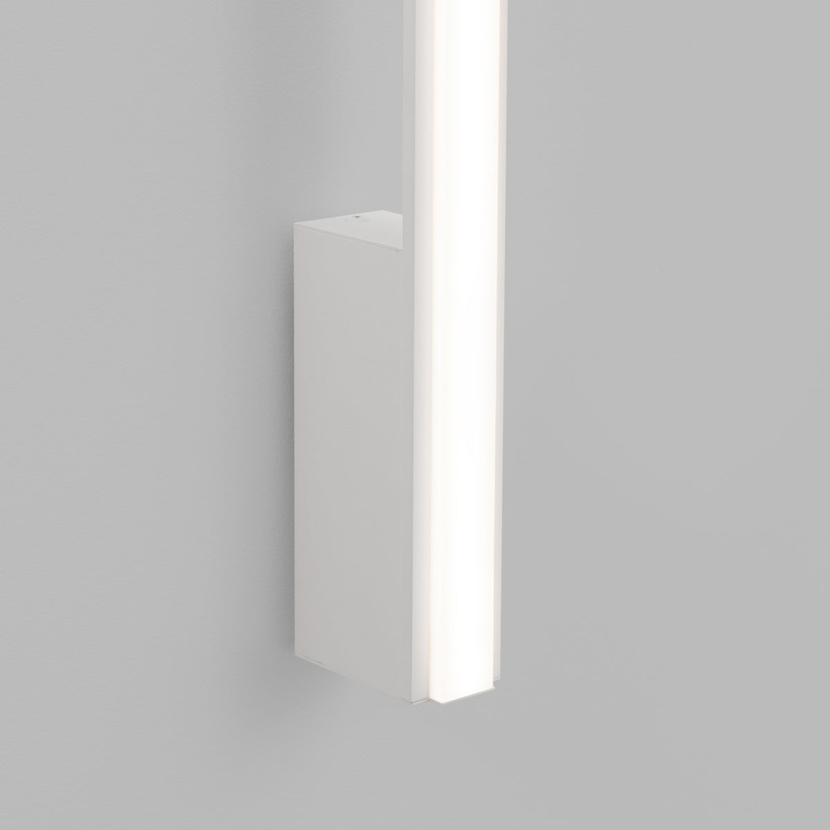 Détail du bas de l'applique : boîtier rectangulaire blanc et diffuseur LED allumé.