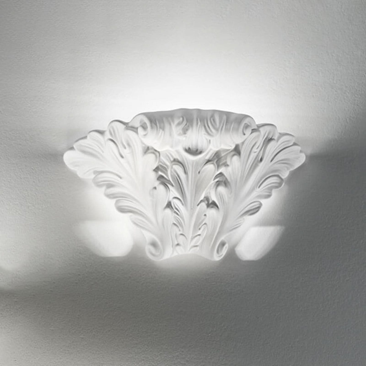Applique murale blanche sculptée, allumée sur un mur, lumière diffusée en haut et en bas.