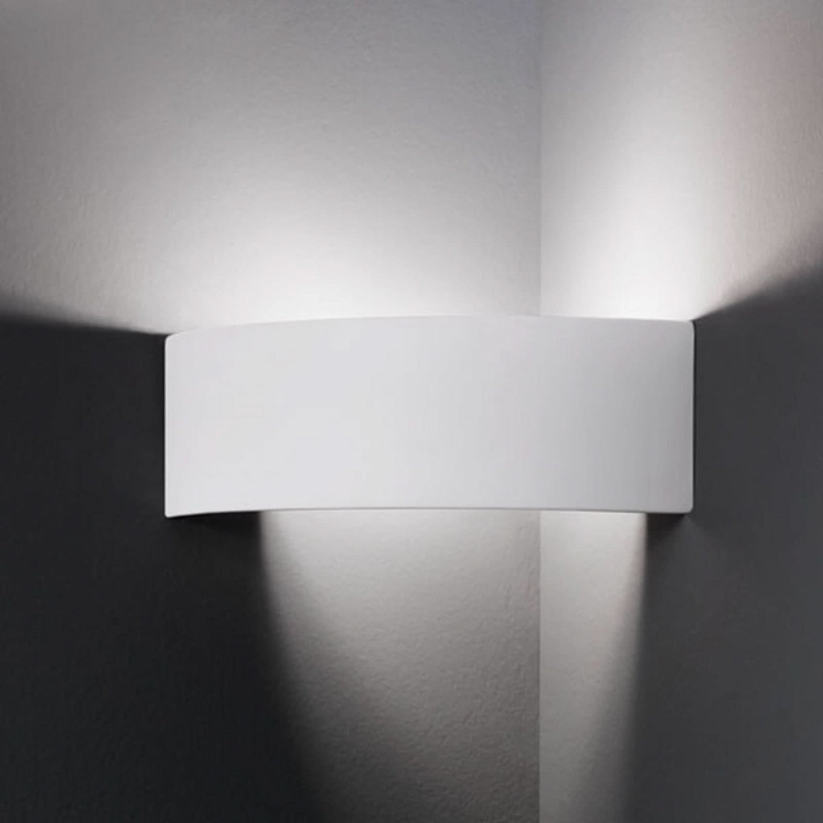 Applique murale blanche allumée sur un mur, diffusant une lumière vers le haut et le bas.