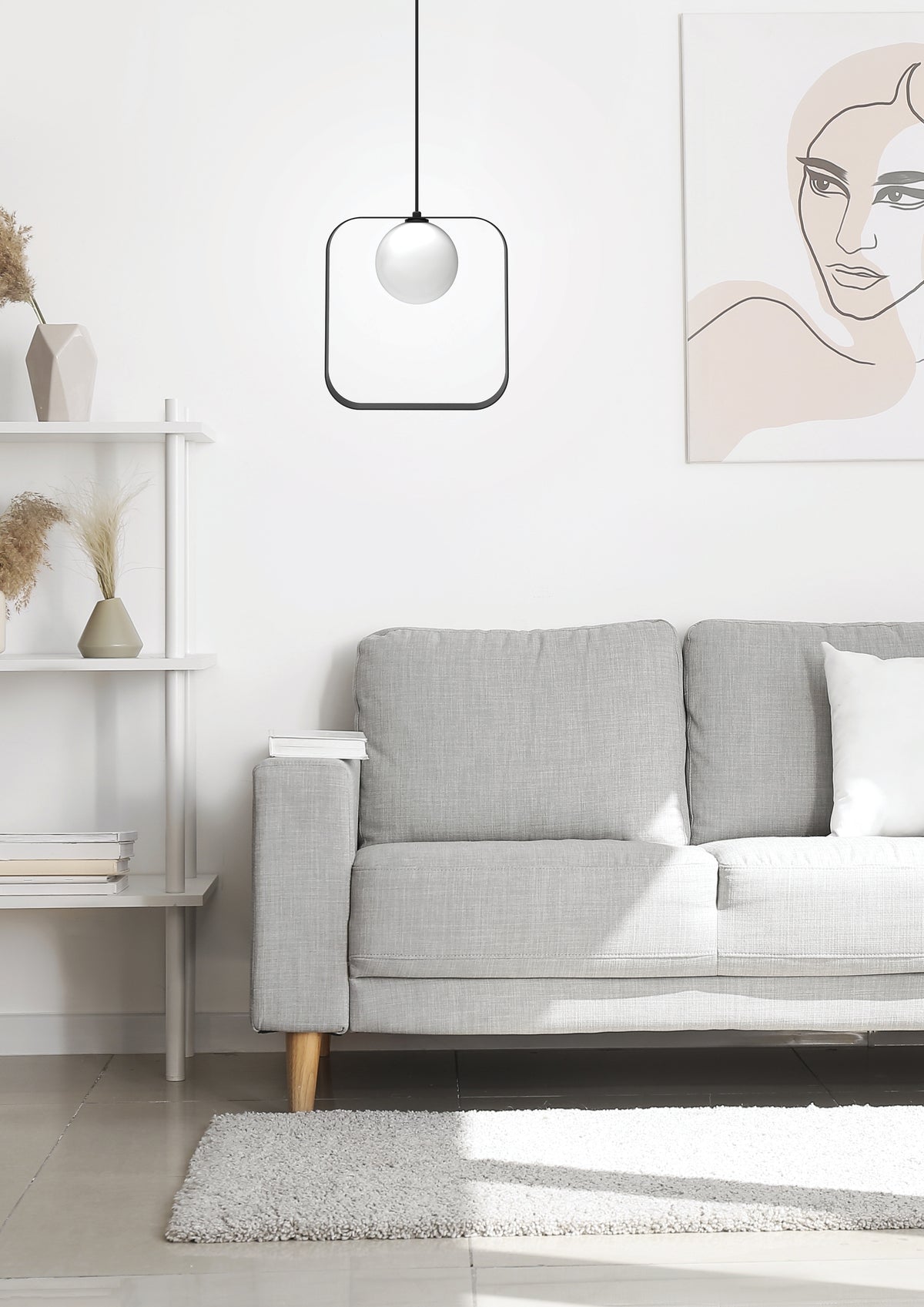 Mise en ambiance du salon avec la suspension allumée au-dessus du canapé gris.