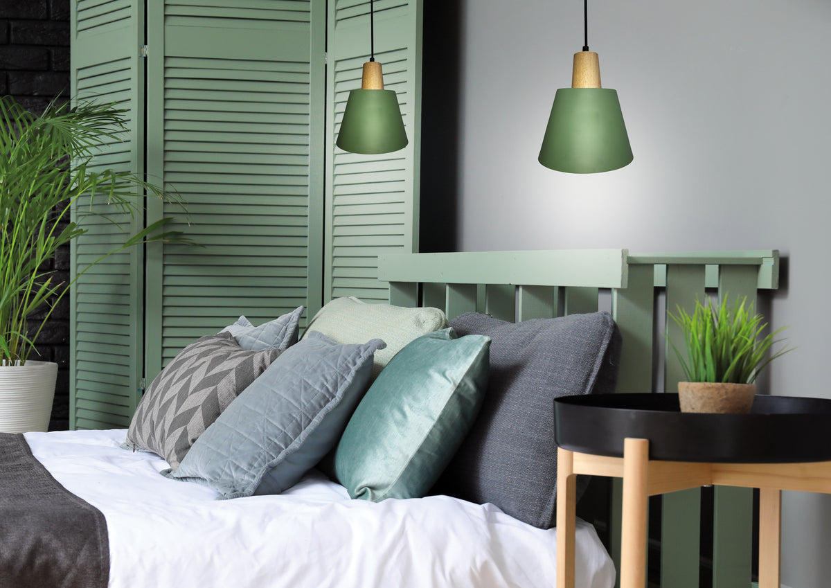 Vue en situation des suspensions vertes éclairant une tête de lit et des coussins colorés