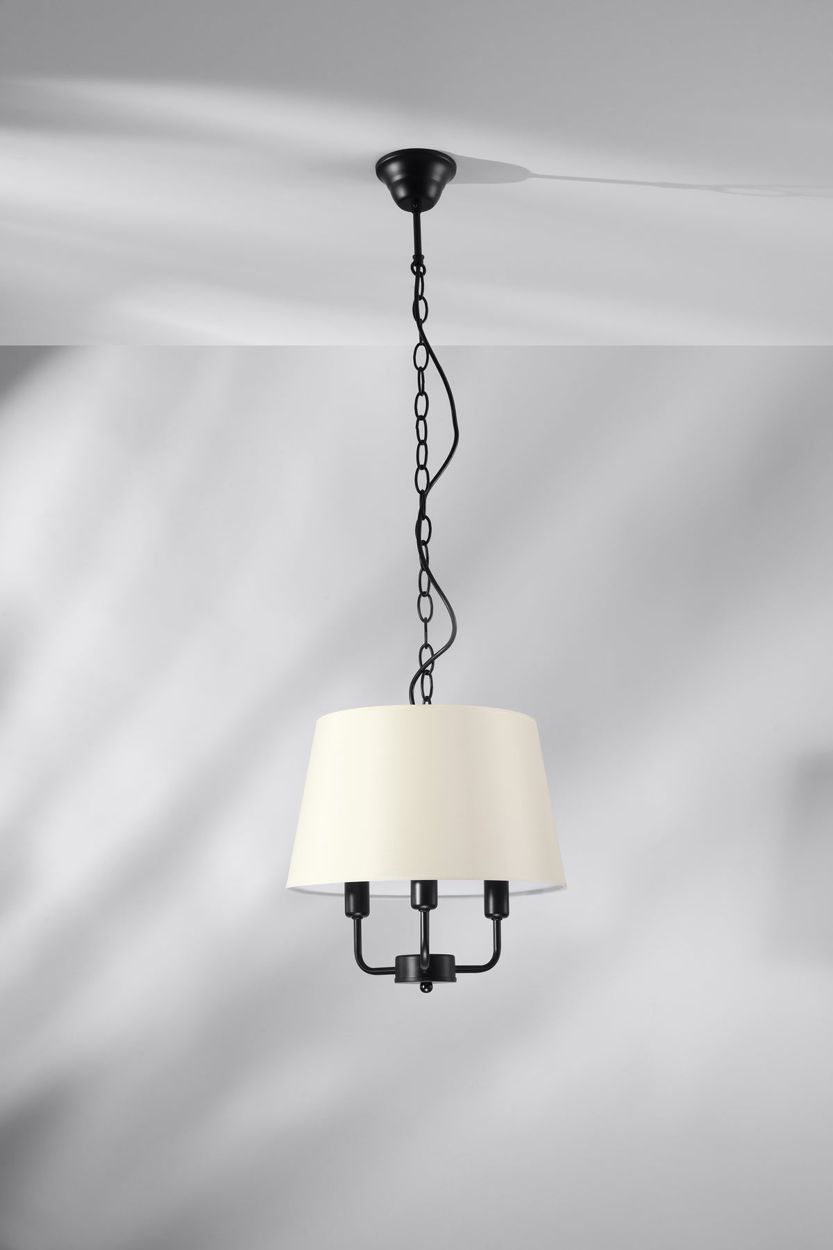 Mise en ambiance sur plafond gris clair, abat-jour beige et chaîne noire visibles.