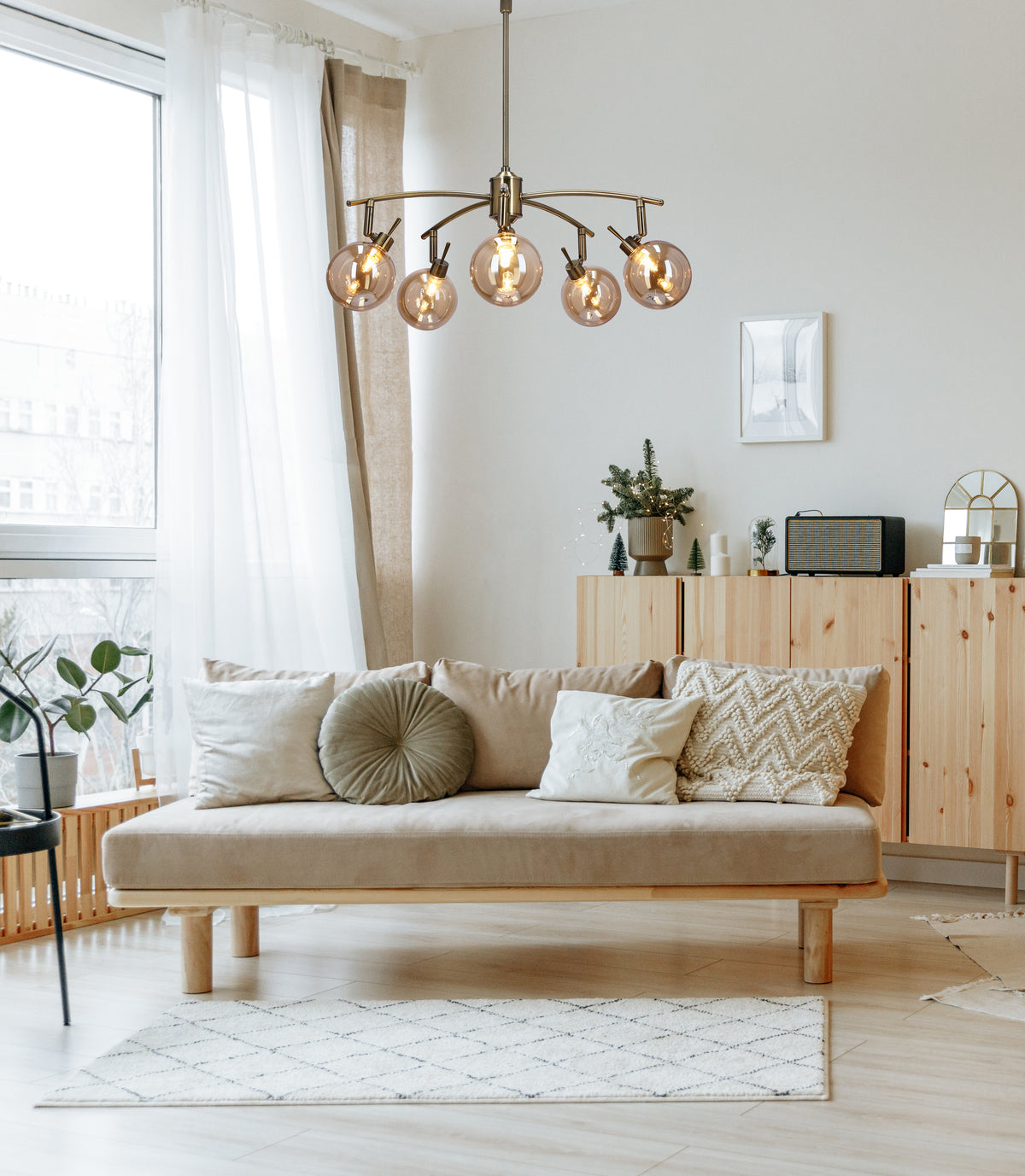 Luminaire suspendu allumé au-dessus d'un canapé beige dans un salon scandinave lumineux