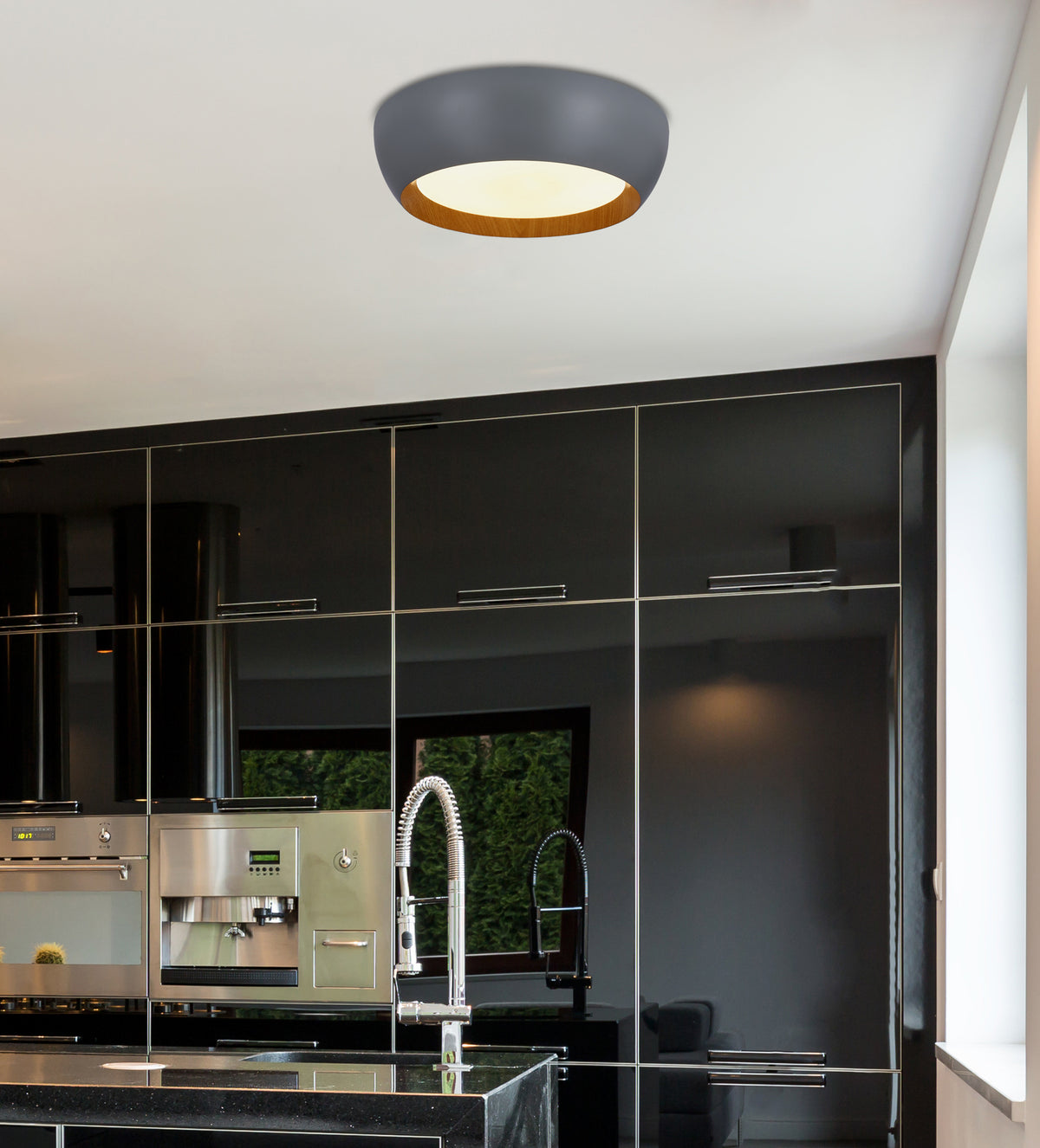 Mise en ambiance du plafonnier allumé au plafond d'une cuisine moderne aux façades noires