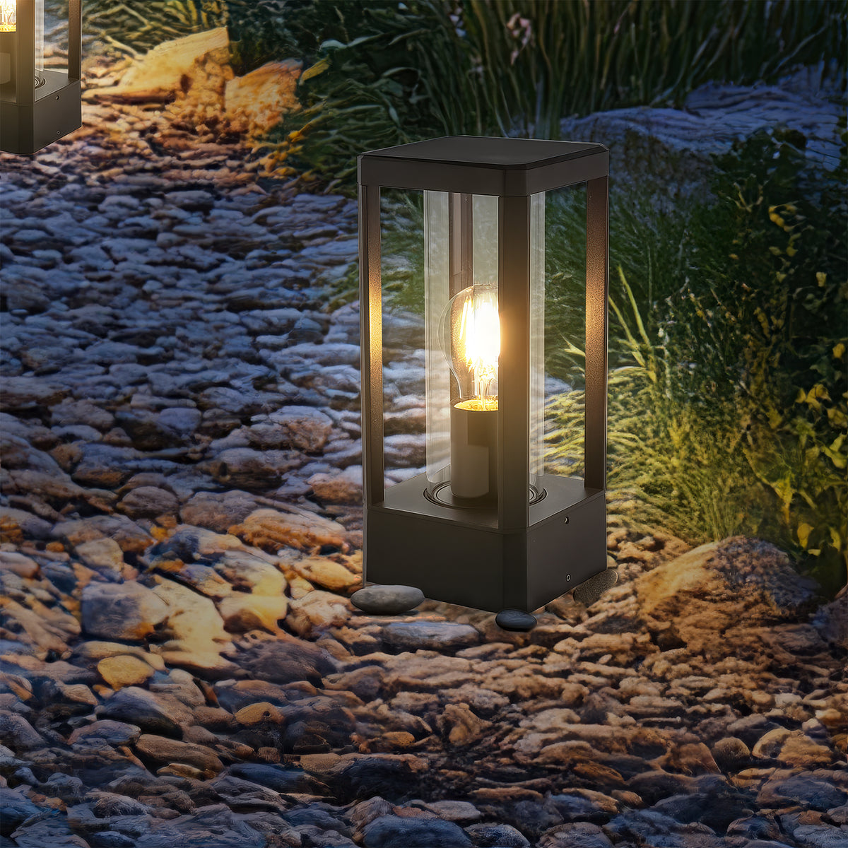 Gros plan nocturne du luminaire allumé, ampoule chaude et reflets sur pierres décoratives.