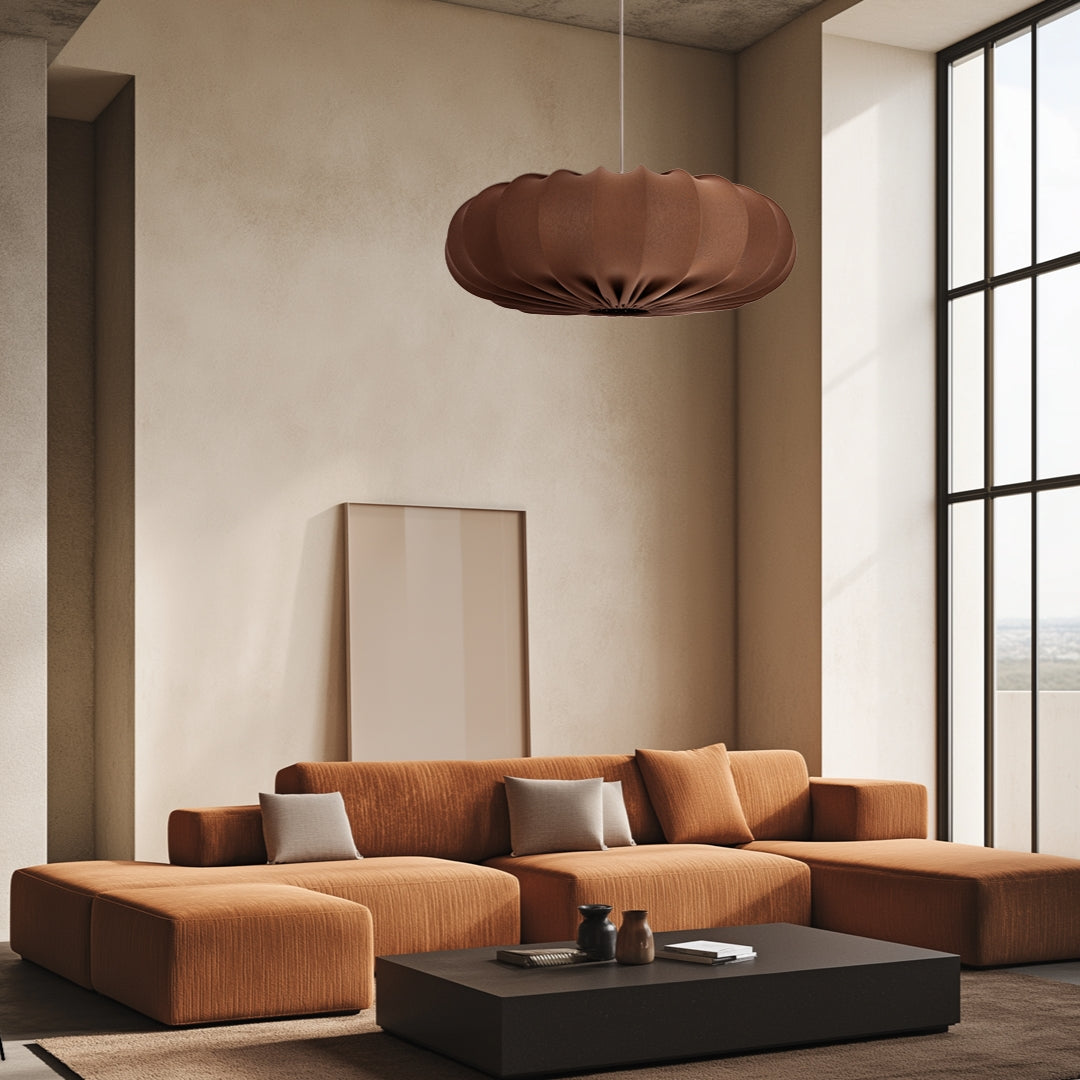 Suspension éclairée dans un salon beige avec canapé rouille, table basse noire et grande fenêtre.