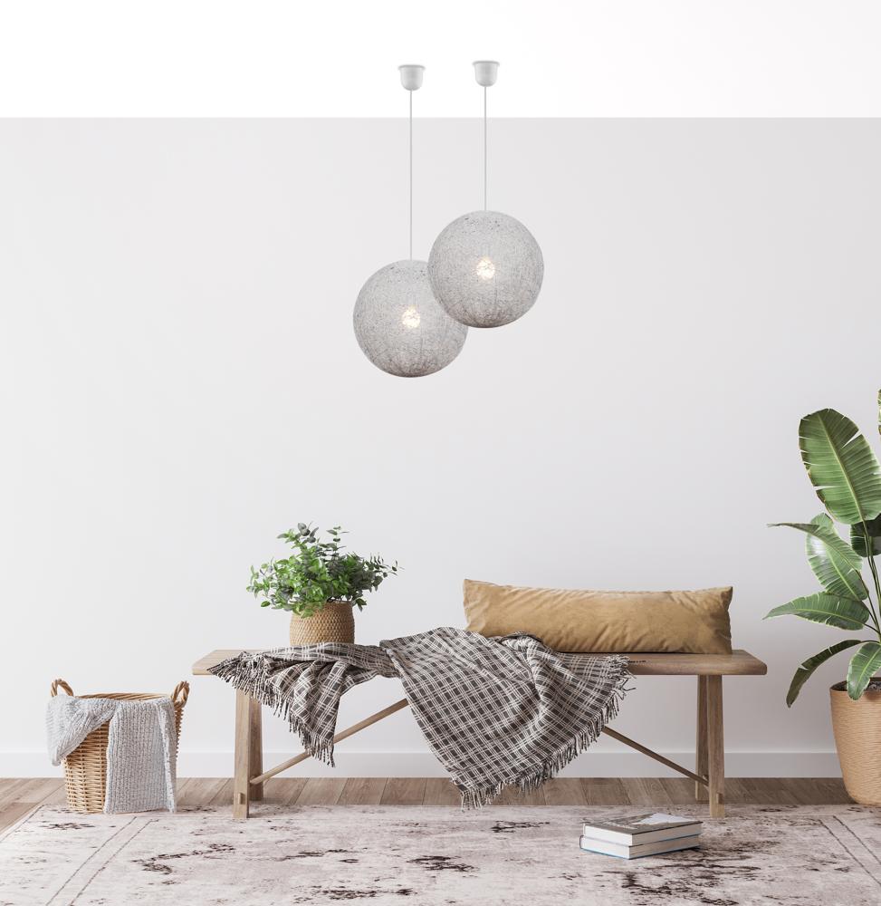 Vue rapprochée des deux globes suspendus éclairés, décor bohème avec plante et plaid
