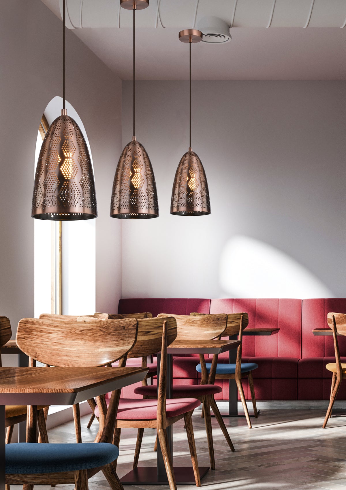 Mise en ambiance dans un café, trois suspensions cuivrées au-dessus de tables en bois.