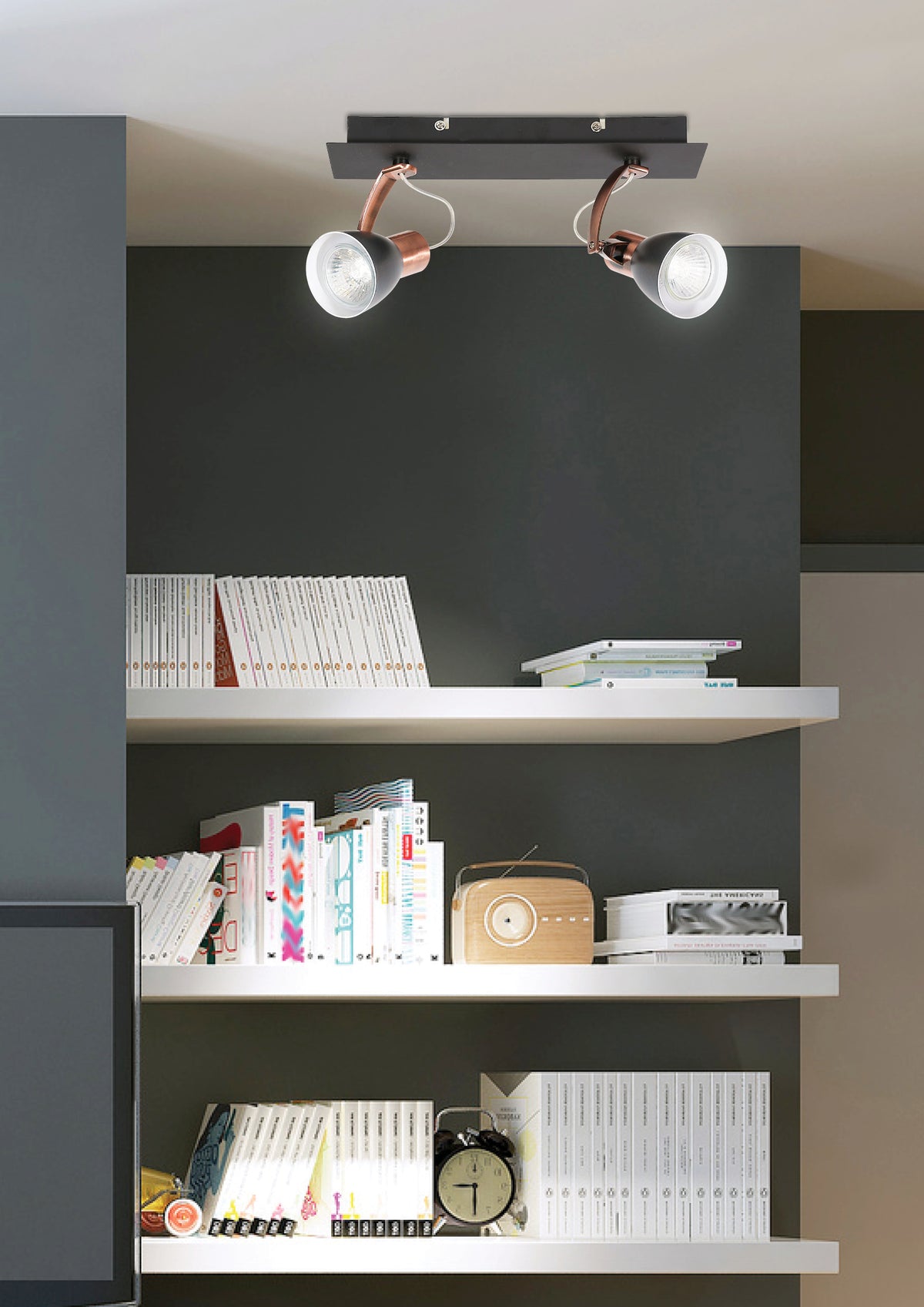 Plafonnier installé au plafond au-dessus d'une bibliothèque, éclairant livres, radio et réveil dans un intérieur sombre.
