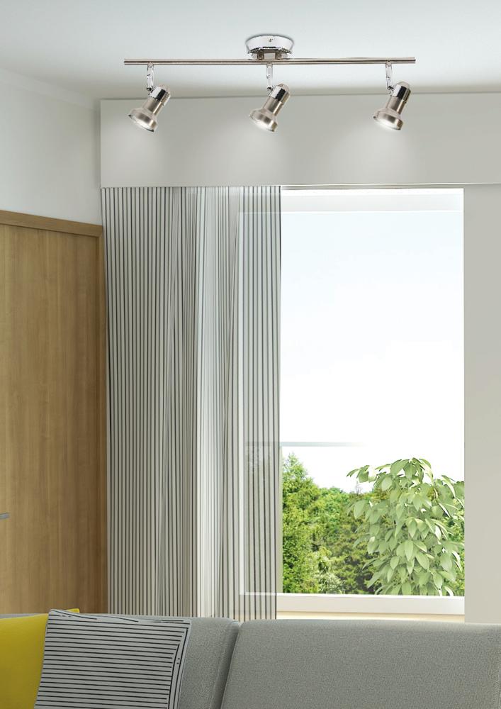 Mise en situation du luminaire orientable dans un salon avec canapé et coussins