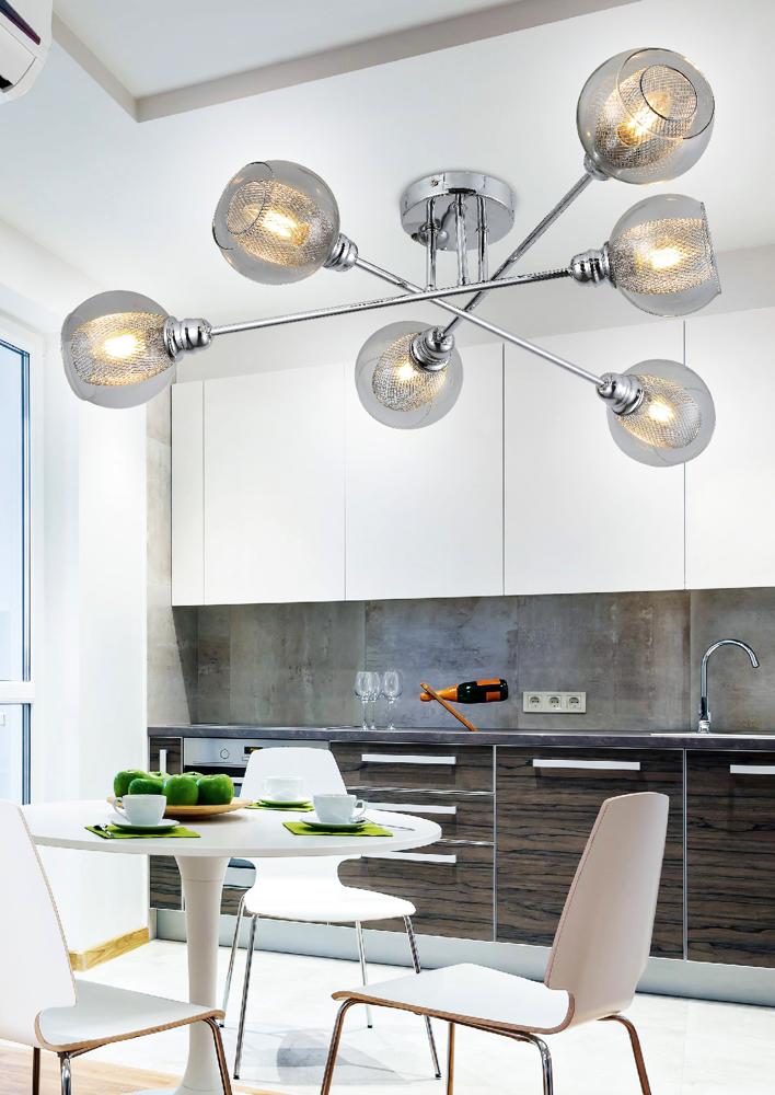 Vue d'ambiance montrant le luminaire allumé dans une cuisine moderne aux meubles blancs et bois.