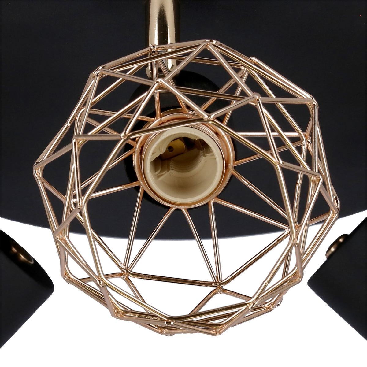 Gros plan sur la cage métallique dorée et la douille noire du luminaire